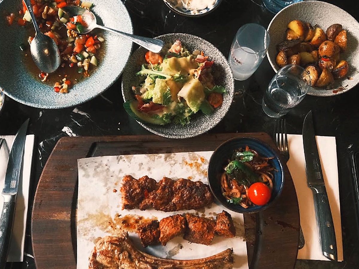 Gedeckte Tafel im Baba Pirzola Berlin mit Selections-Grillbrett (Üçü bir arada), Kuzu Pirzola, Lokum Bonfile, Gavurdağı Salatası, Patates Tava und Rakı