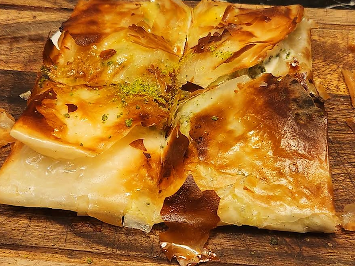 Katmer bei Baba Pirzola Berlin: Knusprige Teigtasche mit Pistazien und Sahne auf dem Holzbrett