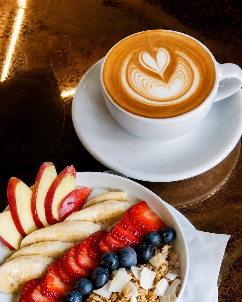 Cappuccino mit Latte Art und eine Frucht-Granola-Schale beim Community-Besuch