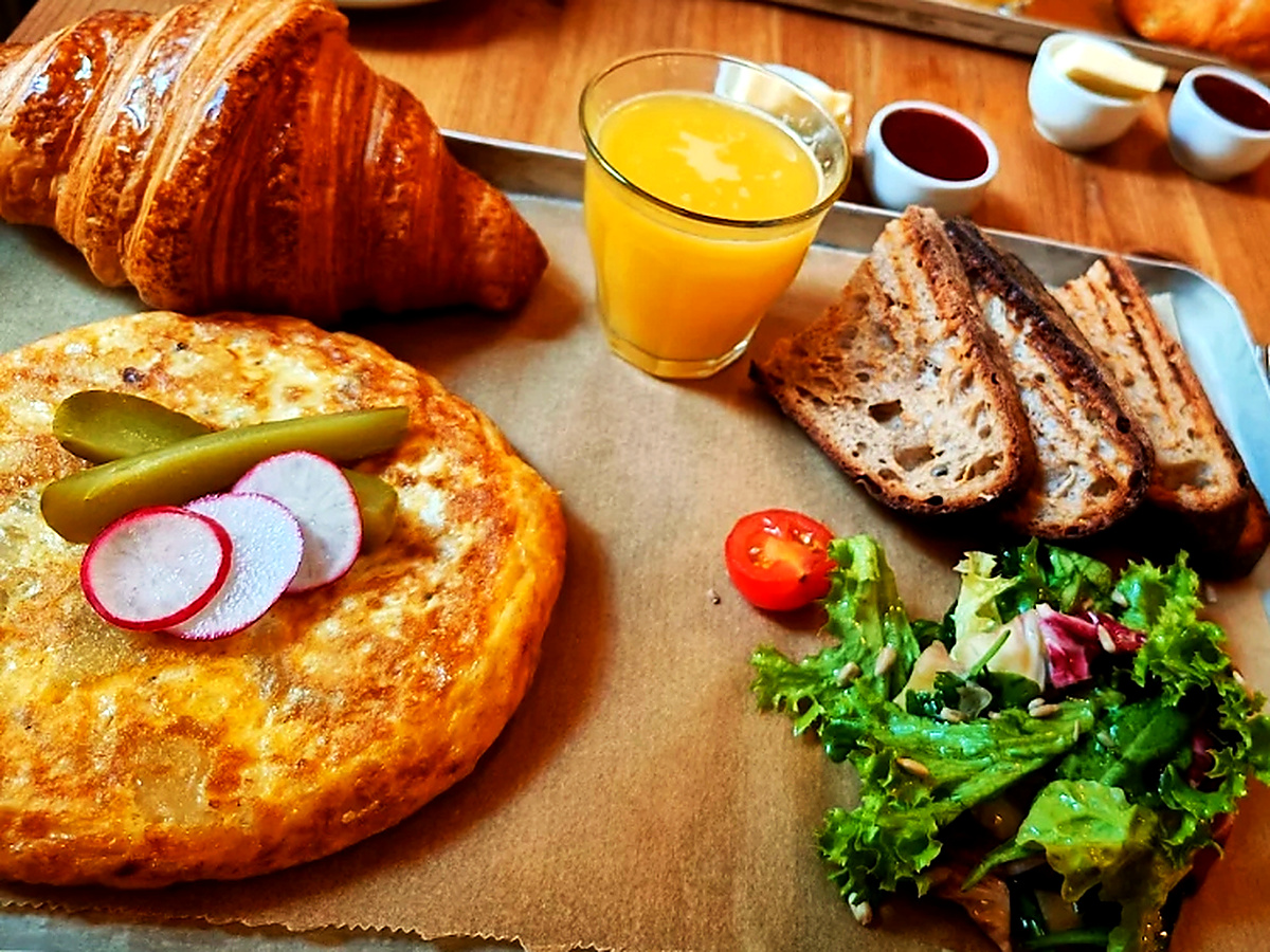 Spanische Kartoffel-Tortilla mit Radieschen und Cornichons, Butter-Croissant, geröstetes Sauerteigbrot und frisch gepresster Orangensaft im Neumanns Café Berlin