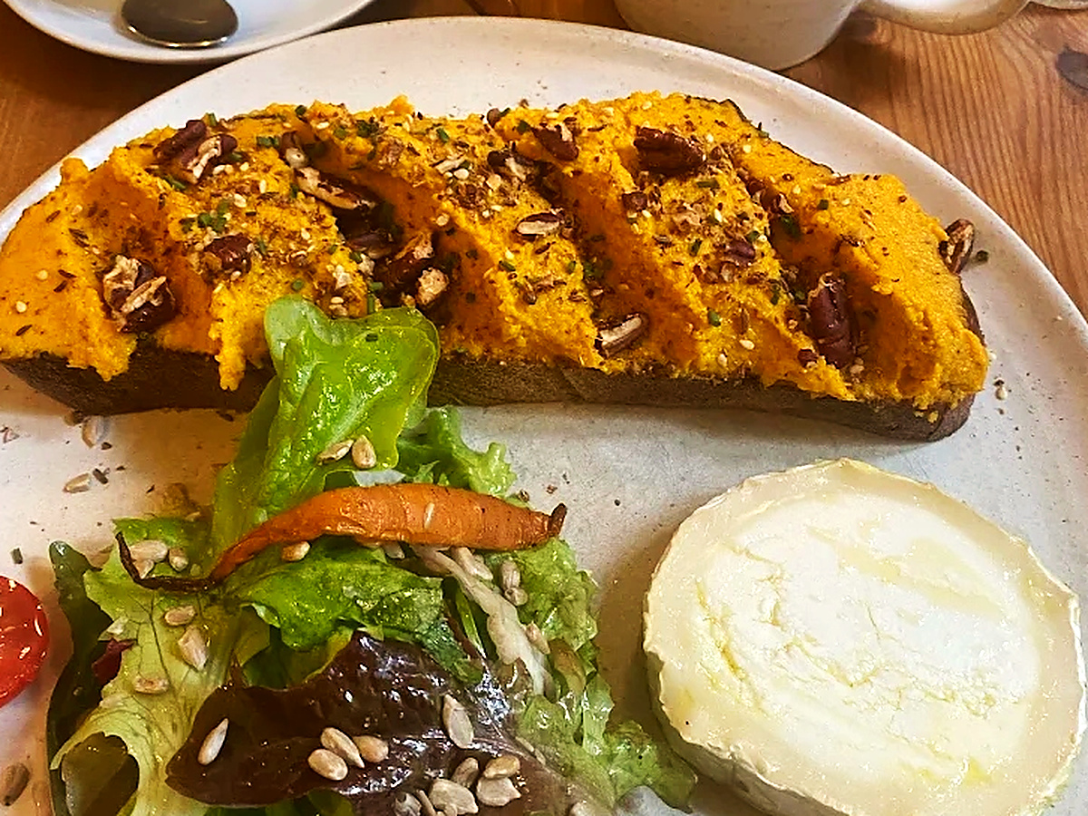 Sauerteig-Stulle mit Karotten-Süßkartoffel-Creme, gerösteten Pekannüssen, cremigem Ziegenkäse, Salat mit geschmorter Karotte und Andraschko Cappuccino im Neumanns Café